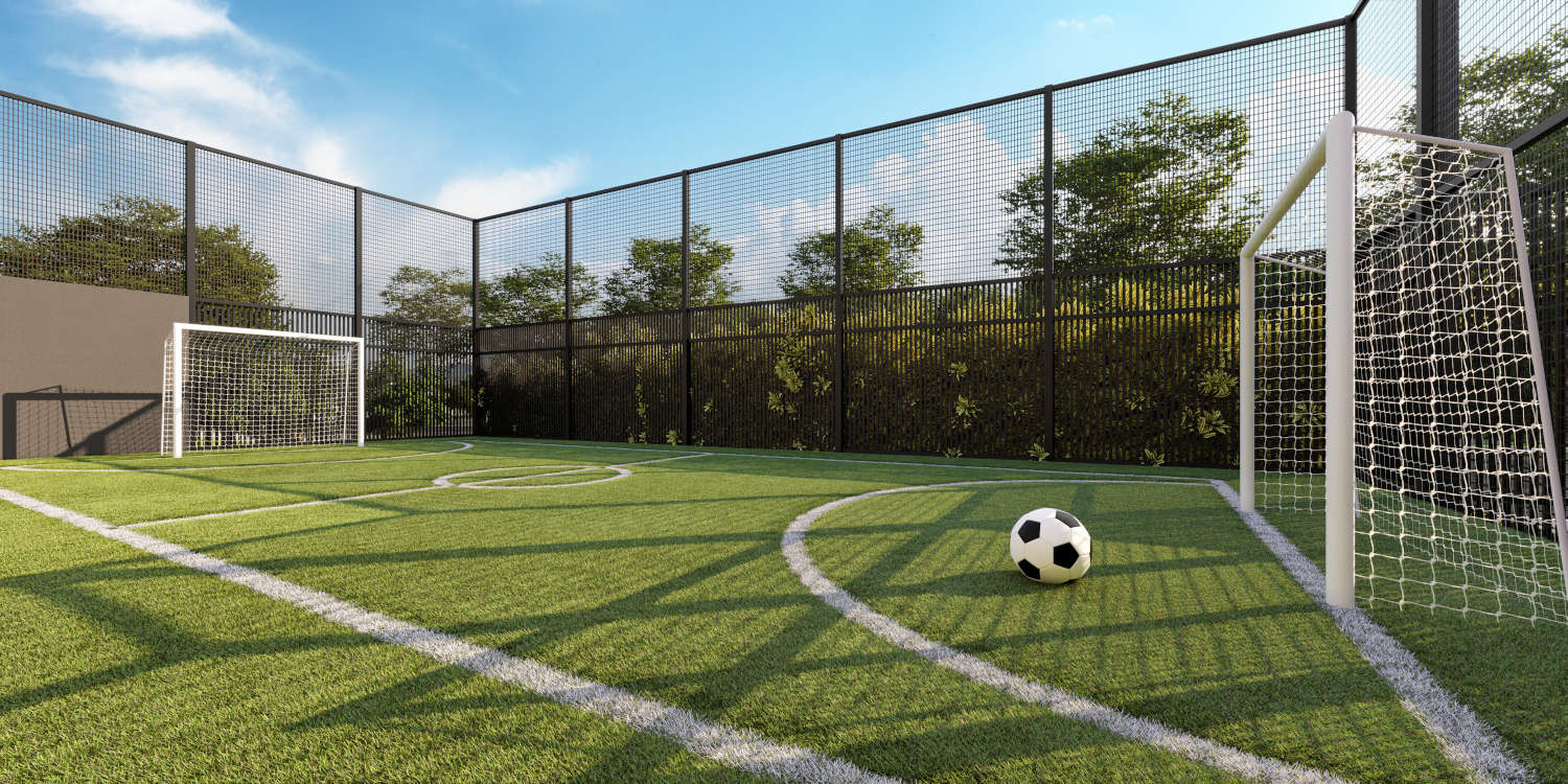Quadra esportiva com grama natural, ideal para partidas de futebol e lazer ao ar livre, oferecendo um ambiente confortável e seguro para esportes.